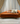 Orange sofa with decorative pillows in a room with curtains and a light floor.