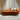 Orange sofa with decorative pillows in a room with curtains and a light floor.
