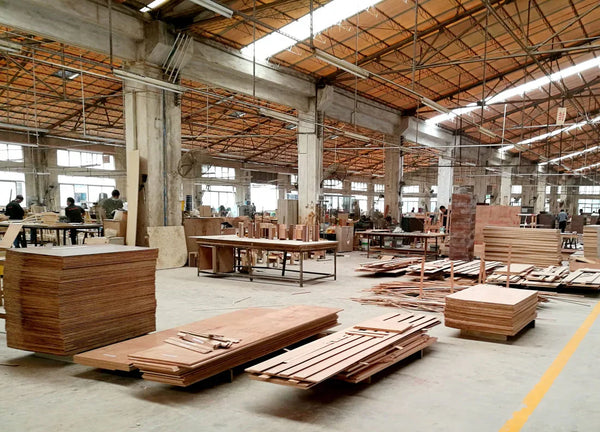 Woodworking workshop with stacks of plywood and workers crafting bespoke furniture pieces