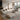 Modern living room with beige sofa, ottoman, and coffee table in a well-lit room.